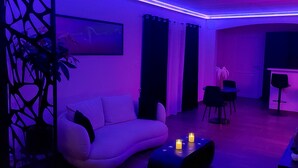 Una sala de estar moderna con un sofá blanco, una mesa de centro con velas y un televisor.