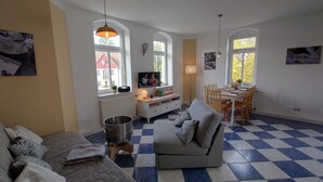 Ein gemütliches Wohnzimmer mit einer Couch, einem Esstisch mit Stühlen, einem Fernseher und einer Heizung.
