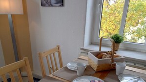 Ein Esstisch ist gedeckt mit Tellern, Tassen und einem Brotkorb.