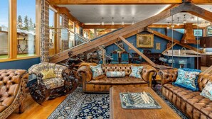 A spacious living room with a large brown leather sofa set, a wooden coffee table, and a chessboard. - Two-bedroom Penthouse with rooftop BBQ, dining & hot tub. (Hood River)