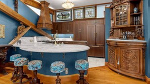 A kitchen with a central island, bar stools, wooden cabinets, and decorative elements. - Two-bedroom Penthouse with rooftop BBQ, dining & hot tub. (Hood River)