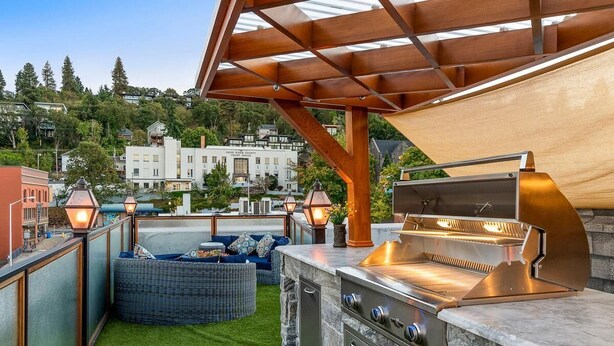 An outdoor patio with a grill and seating area, overlooking a residential neighborhood. - Two-bedroom Penthouse with rooftop BBQ, dining & hot tub. (Hood River)