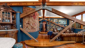 A room with a wooden staircase, a large tapestry, and a collection of framed pictures on the walls. - Two-bedroom Penthouse with rooftop BBQ, dining & hot tub. (Hood River)