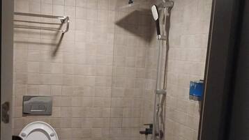 A bathroom with a toilet, a shower, and a sink.