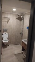 A bathroom with a toilet, a shower, and a sink.