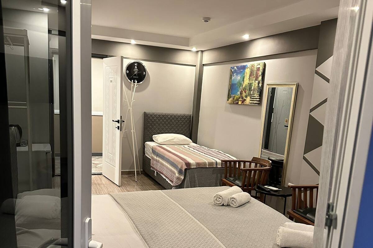 Moderni hotellihuone, jossa on suuri sänky, yöpöytä, tuoli, työpöytä ja peili.