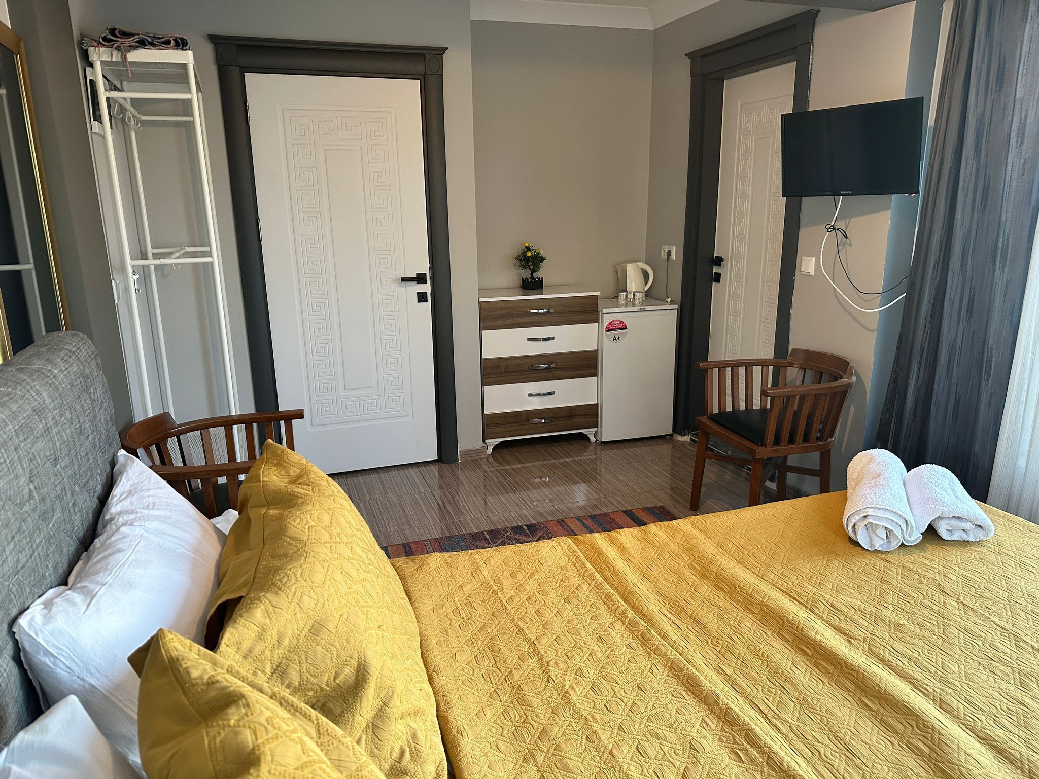 Een hotelkamer met een bed, een bureau, een stoel, een televisie en een kledingkast.