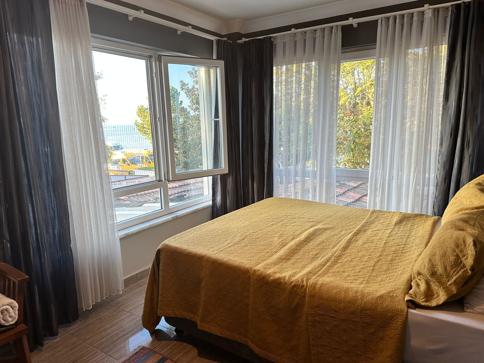 Un dormitorio con cama, ventana y cortinas.