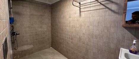 A small bathroom with a shower, a toilet, and a sink with soap.