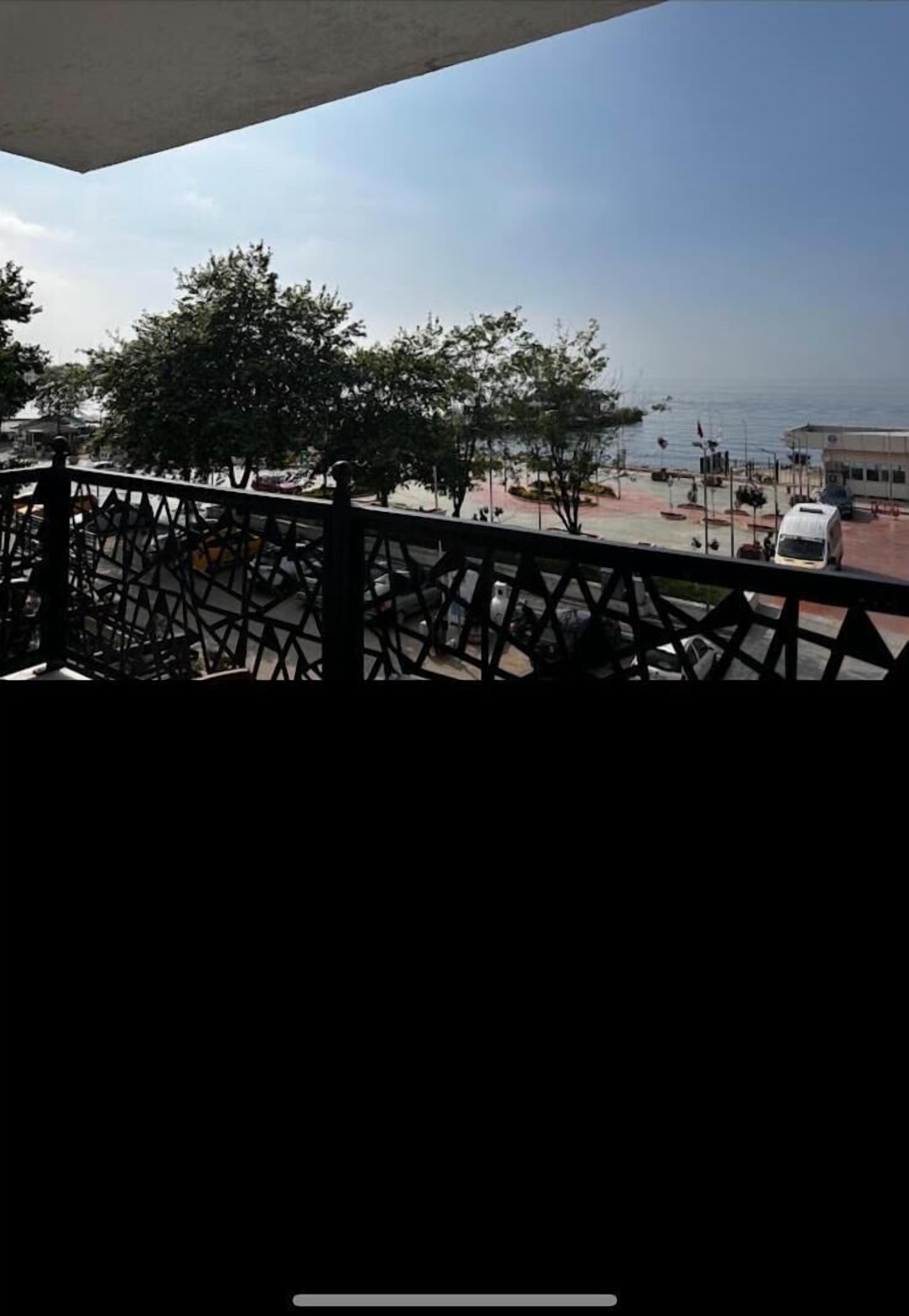 A balcony with a view of a street, trees, and a building across the road.