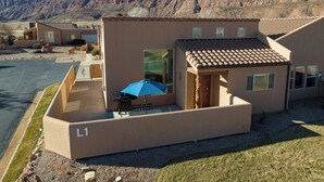 A modern building with a flat roof and a patio area with a table and chairs. - Slickrock Sanctuary (Moab)
