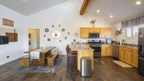 A modern kitchen with wooden cabinets, a central island, and a dining area with benches. - Slickrock Sanctuary (Moab)