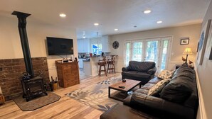 A living room with a fireplace, a sofa, a coffee table, and a TV. - Your Peaceful Home on the Klamath River (Montague)