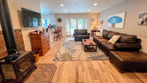 A spacious living room with a fireplace, a sofa, a coffee table, and a TV mounted on the wall. - Your Peaceful Home on the Klamath River (Montague)