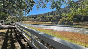 A wooden bridge with a railing, leading to a river with a forested hillside in the background. - Your Peaceful Home on the Klamath River (Montague)