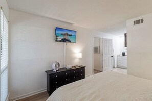 A bedroom with a bed, a dresser, a lamp, and a painting of a beach scene. - 50 Yard Line

 (College Station)