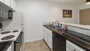 A modern kitchen with white cabinets, a black countertop, and a dishwasher. - 50 Yard Line

 (College Station)