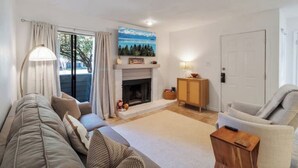 A living room with a sofa, a chair, a fireplace, a lamp, and a painting on the wall. - 50 Yard Line

 (College Station)
