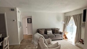 A spacious living area with a sofa, a dining table, and a chair. - 50 Yard Line

 (College Station)