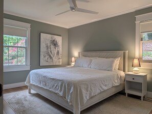 Ein Schlafzimmer mit einem Bett, Nachttischlampen, einem Deckenventilator und einem Fenster mit Blick auf rosa Blüten.