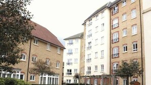 Une cour intérieure bordée de deux immeubles à plusieurs étages, l’un avec un toit rouge et l’autre avec des balcons.