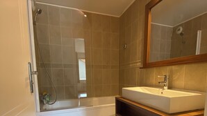 Un bagno moderno con vasca, lavandino e doccia.