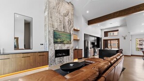 A modern living room with a leather sofa, a fireplace, a kitchen area, and a dining space. - Iwtbk4 (Keystone)