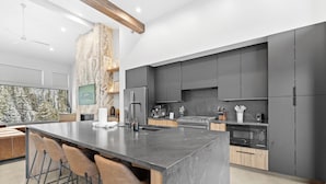 A modern kitchen with a large island, dark cabinetry, and a stone accent wall. - Iwtbk4 (Keystone)