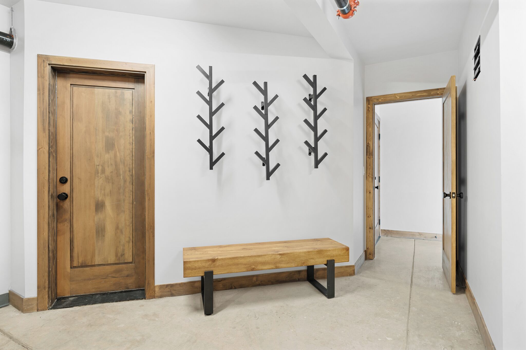 A hallway with a wooden door, a bench, and three wall-mounted leaf-shaped decorations.