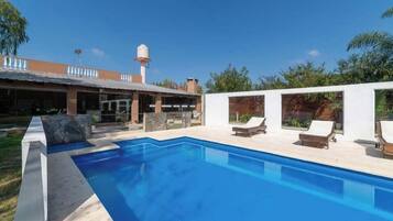 Alberca techada, alberca al aire libre y sombrillas en la alberca