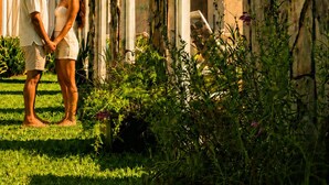 A couple standing in a garden with a stone wall and a building in the background. - Buenos Aires de Ezeiza Resort Vacacional - Dos Departamentos (La Unión)