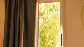 A hotel room with a bed, a window with curtains, and a view of greenery outside. - Buenos Aires de Ezeiza Resort Vacacional - Dos Departamentos (La Unión)