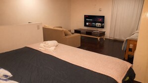 A hotel room with a bed, a sofa, a TV, and a wooden side table. - Buenos Aires de Ezeiza Resort Vacacional - Dos Departamentos (La Unión)