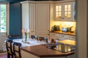 Una cocina con armarios blancos, una mesa de comedor con sillas y un microondas en la encimera.