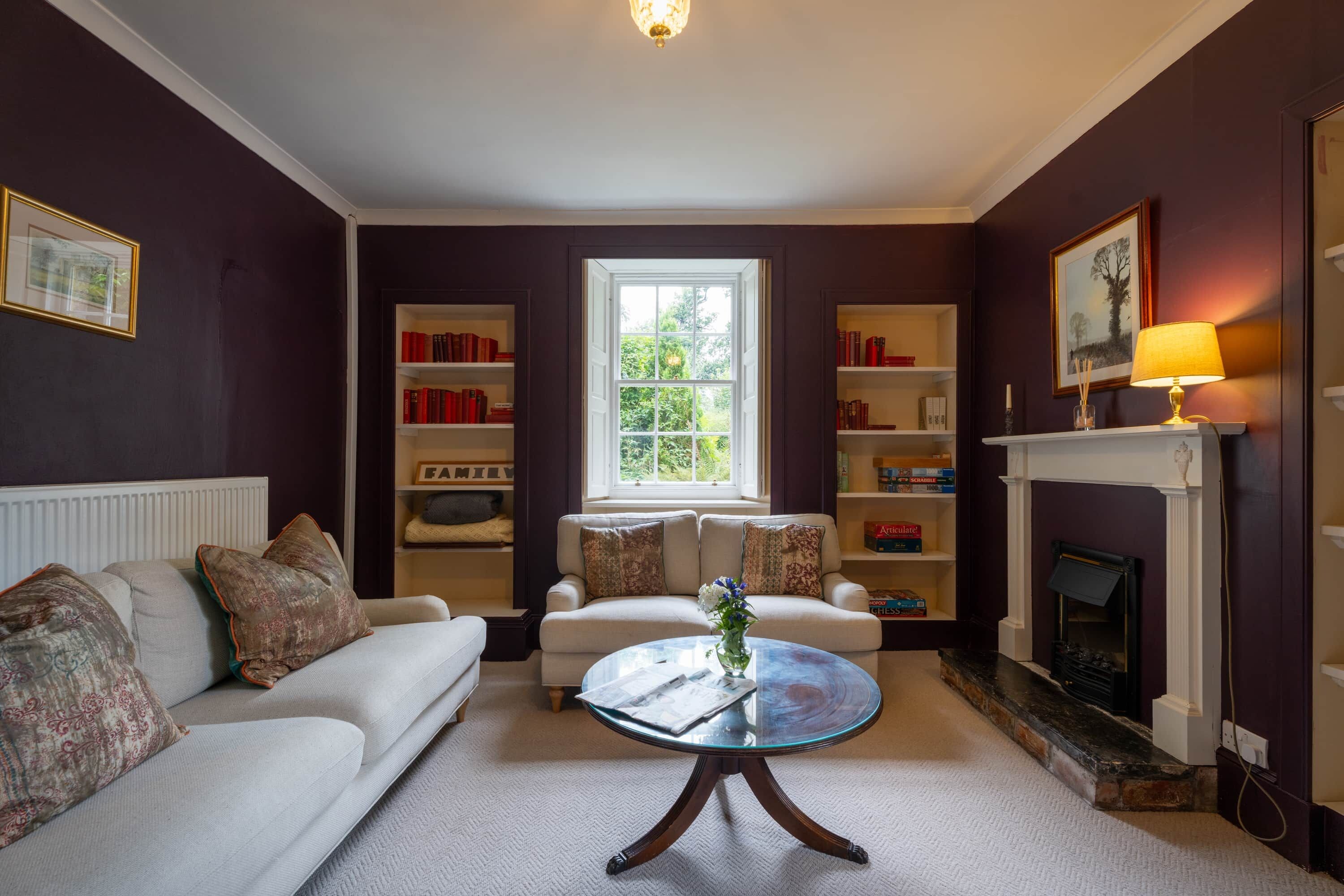 A living room with a white sofa, a glass coffee table, a fireplace, and bookshelves.