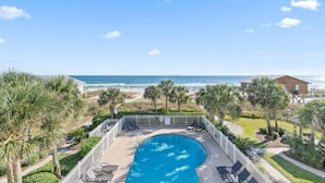 Ein Poolbereich mit Blick auf Strand und Meer.