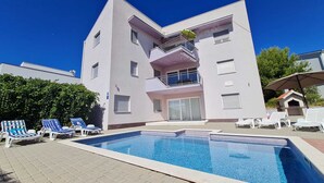 A modern two-story building with a swimming pool, lounge chairs, and a barbecue area. - Apartment Barbara  in Okrug Gornji (Okrug Gornji)