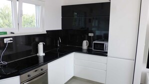 A kitchen with black countertops, white cabinets, a built-in oven, a microwave, and a window with curtains. - Apartment Barbara  in Okrug Gornji (Okrug Gornji)
