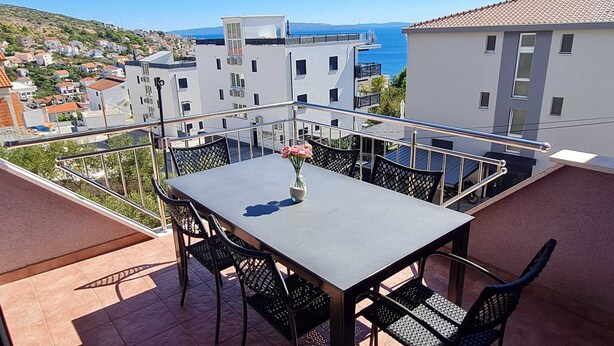 A balcony with a table and chairs, overlooking a coastal town. - Apartment Barbara  in Okrug Gornji (Okrug Gornji)