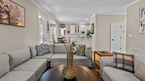 A living room with a beige sofa, a coffee table, and a decorative vase. There is a dining area in the background with a wooden table and chairs. - Near Downtown Cary and Raleigh - 5 room King beds, walking distance to Bond Park (Cary)