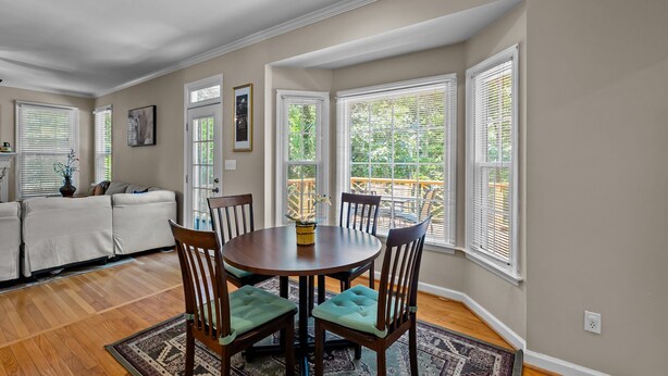 A dining area with a round table, chairs, and a view of the outdoors through large windows. - Near Downtown Cary and Raleigh - 5 room King beds, walking distance to Bond Park (Cary)
