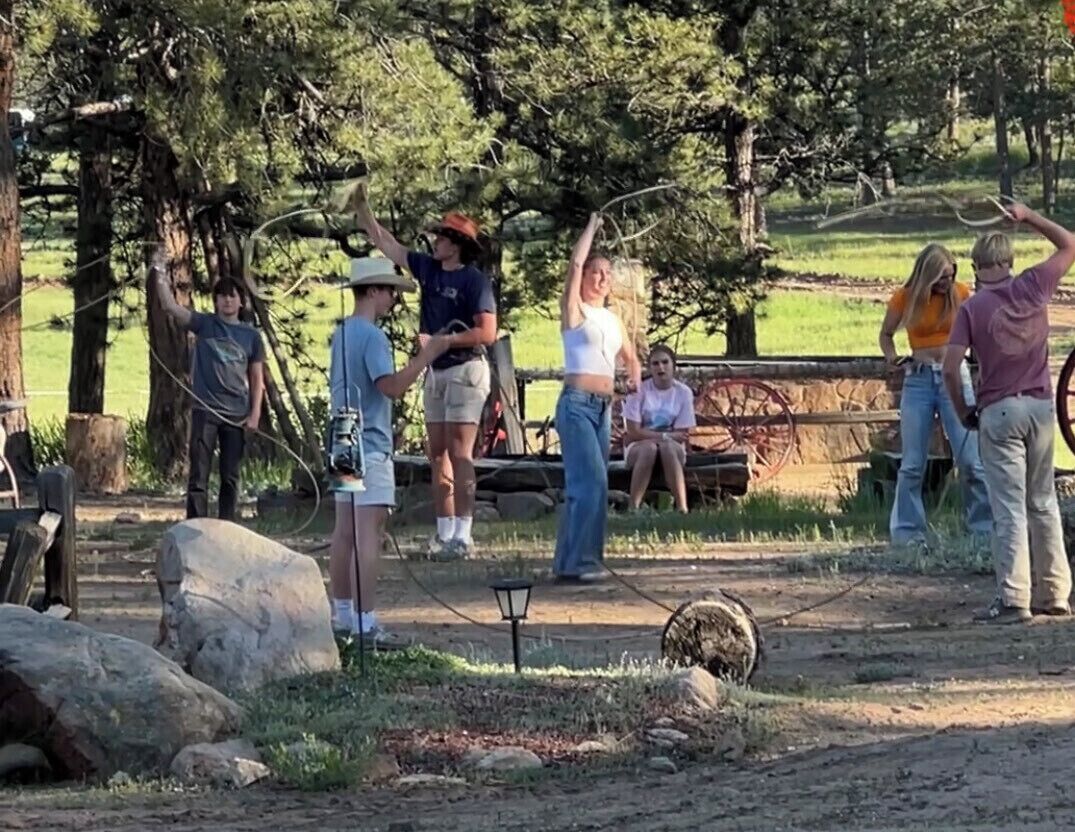 Un groupe de personnes se trouve dans un endroit en plein air, avec des arbres et un chemin de terre.