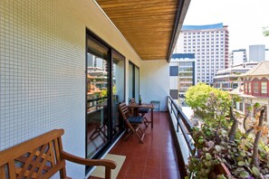 A balcony with a wooden bench, a table with chairs, and a potted plant. - VIVA Belos Ares - 3 bedrooms (Porto)