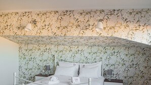 Une chambre à coucher avec un lit, des tables de chevet, une chaise, une petite table et une plante en pot.