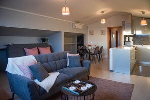 Eine moderne Wohnung mit grauem Sofa, einem Essbereich und einer Küche mit Edelstahlgeräten.