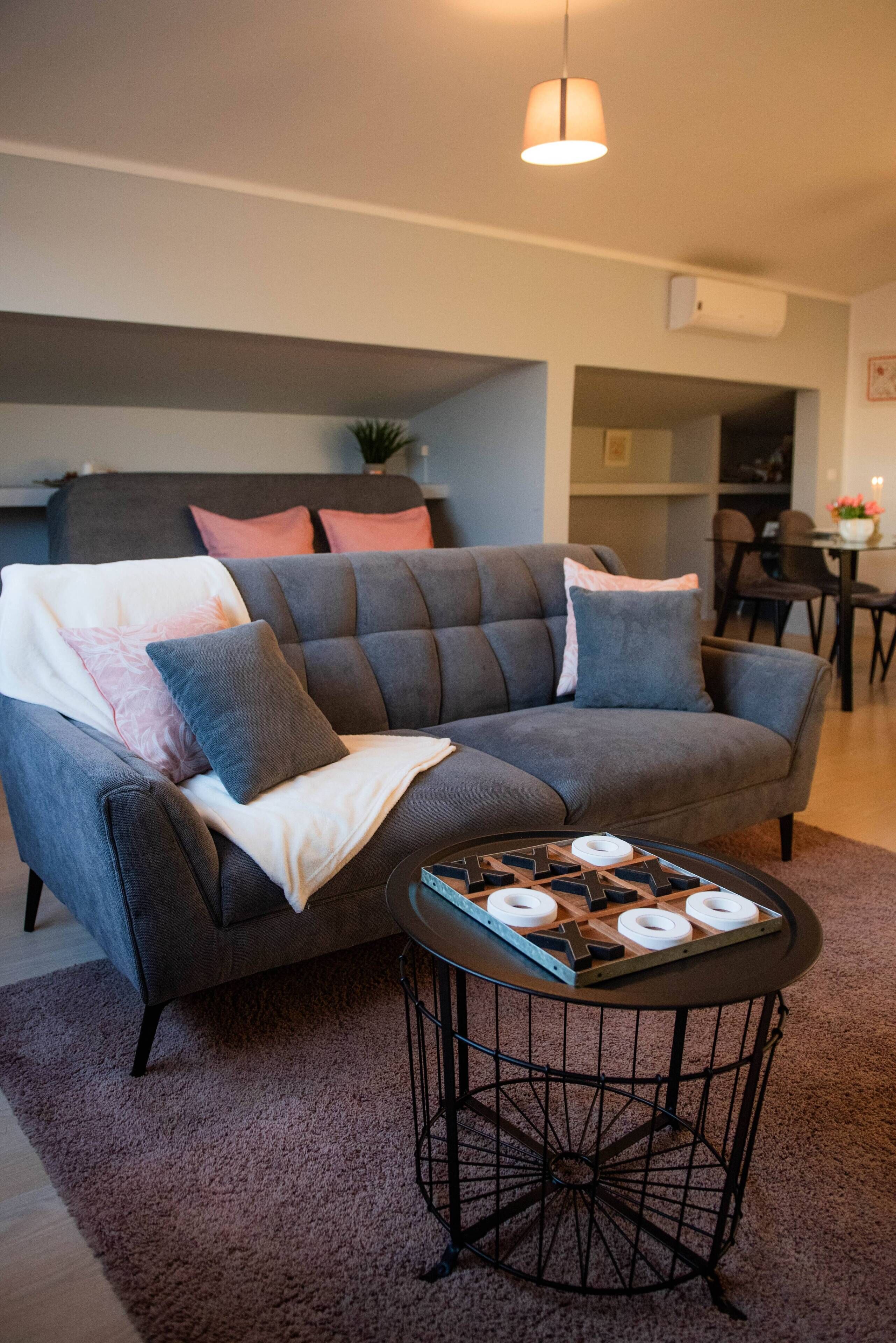 A modern living room with a grey sectional sofa, a small round coffee table, and a pendant light.