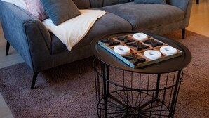 Un salon moderne avec un canapé d’angle gris, une petite table basse ronde et un luminaire suspendu.