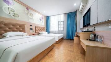 A hotel room with two beds, a wooden floor, a TV, a desk, and a window with curtains.