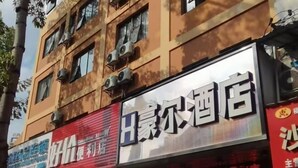 Un edificio con varias indicaciones, incluyendo una para un hotel y otra para una tienda de conveniencia.