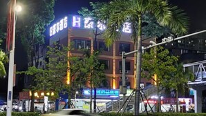 Un hotel con un letrero llamativo, rodeado de árboles y otros edificios.